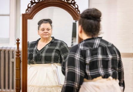 Keala Settle standing in front of a mirror with a checked shirt and white skirt