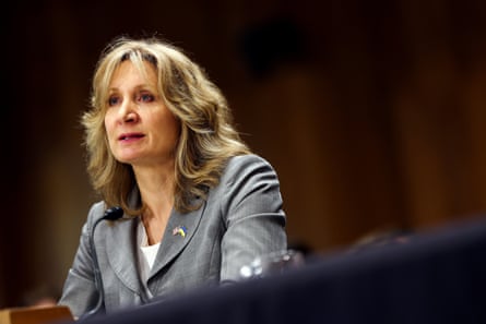 a woman in a grey suit speaks into a microphone