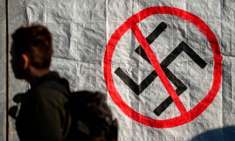 A man walks past a logo of the Nazi swastika