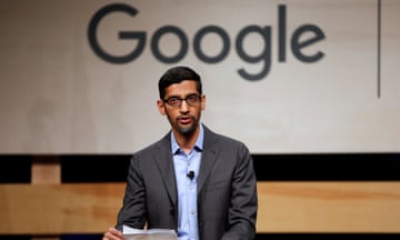 Man wearing glasses, grey suit and blue shirt stands in front of 'Google' logo