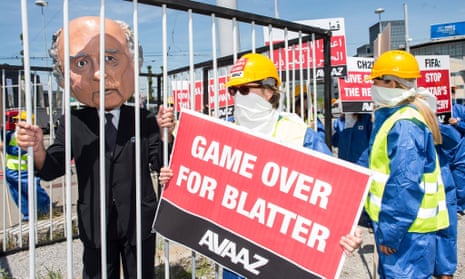 An activist wears a giant head depicting Sepp Blatter inside a cage during a protest by the Avaaz.org