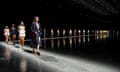 A long line of models walk along a line of light in Gucci clothing.