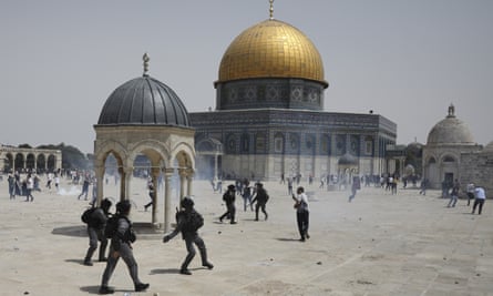 Palestinians run from sound grenades thrown by Israeli police in front of the Dome of the Rock in the al-Aqsa mosque complex in Jerusalem, on 21 May.