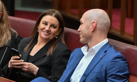 Jacqui Lambie and David Pocock smile and chat with each other in the red-coloured Senate chamber