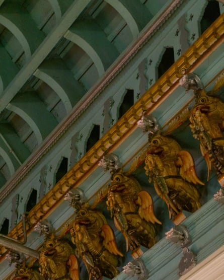 A line of gold carved dragons along a cornice on a turquoise wall