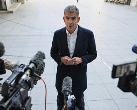 Brittin being interviewed surrounded by mics