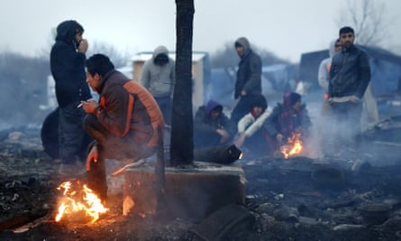 Migrants keep warm during the dismantling of the ‘Jungle’ makeshift camp in Calais.