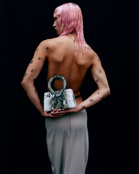 Seorang model memegang tas Ana dari Luar.  Ini adalah tas berbentuk persegi klasik dengan pegangan bundar melingkar. 