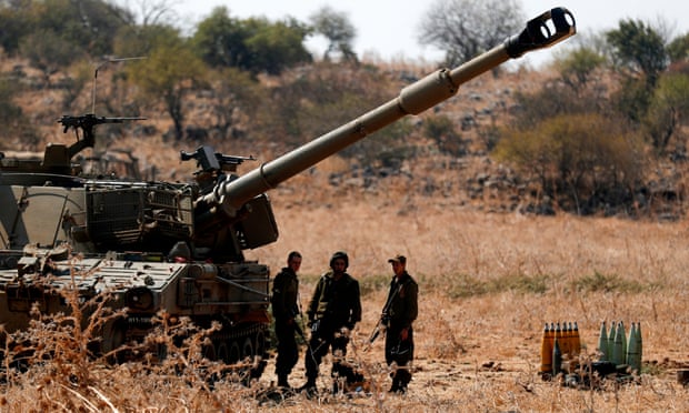 Israeli soldiers stand near artillery units deployed near the Israeli-Lebanon border
