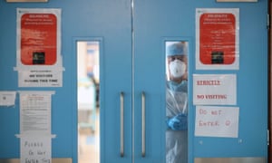A nurse in PPE stares through the doors of a Covid ward in the early stages of the Covid-19 pandemic.
