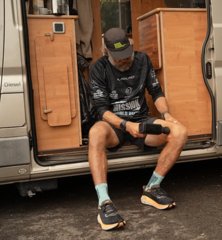 Jackson sits in the doorway of his camper van running a massaging tool over the inside of one knee.