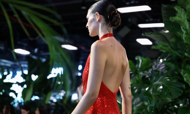 A model wearing a red sequined dress walks the runway for Michael Kors' Spring 2023 show. 