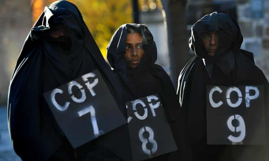 Activists wearing black hoods cloaks marked Cop7, Cop8, Cop9 and take part in a mock funeral at Glasgow Necropolis during Cop26.