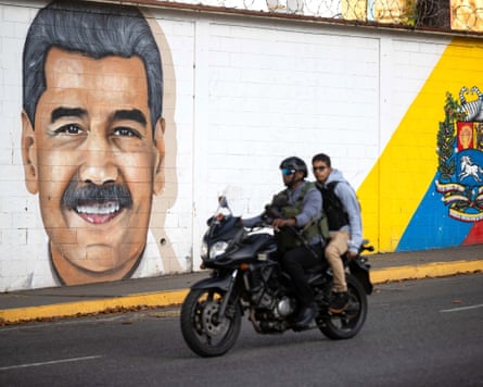 A motorcycle passes a mural of Venezuelan president Nicolás Maduro