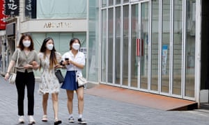 Women wearing masks walk in a shopping district in Seoul, South Korea.