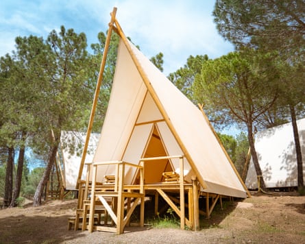 Exterior view of a triangular Anza tent, surrounded by pines, at Los Villares campsite in Córdoba, Spain, on a sunny day.