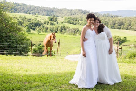 Two women in white dresses pose for a photo during their commitment ceremony