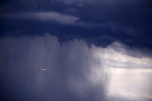 A Qantas Boeing 737-800 plane flies through heavy rain as the storm moves towards the city