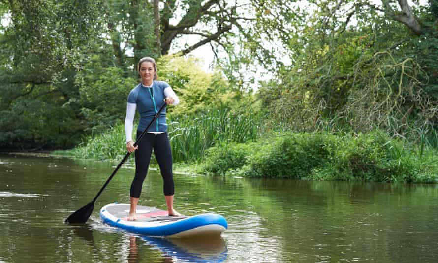 Young woman paddleboarding on the river.