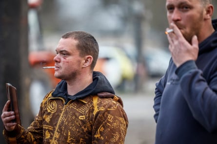 A wounded man takes a video with his phone as another man stands beside him in Kyiv