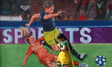An Indian woman walks past a Women's Asian Cup mural