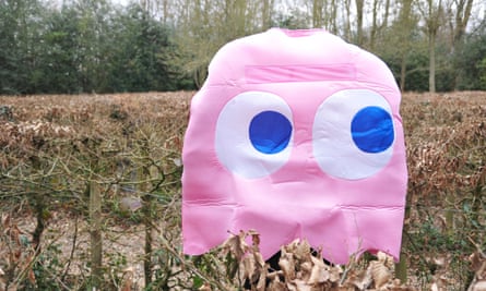 A pink ghost with blue and white eyes in a park.