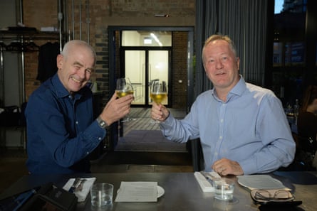 Both men smile and raise their glasses.