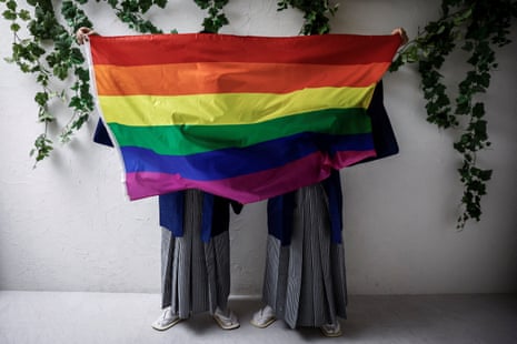 A gay couple pose with a rainbow flag hiding their faces