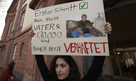 Serda Alshehabi holds a banner about her father’s internment in Syria in front of the court in Koblenz, Germany.