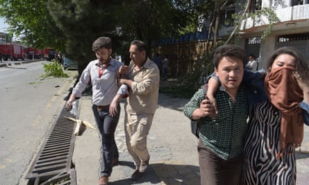 Afghan men provide assistance to the wounded at the site of the car bomb attack in Kabul