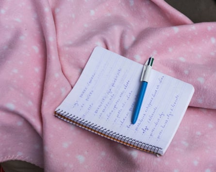 A notebook used by a Moroccan migrant to study Spanish lies on pink and white spotted bedding at a reception centre in Ceuta.