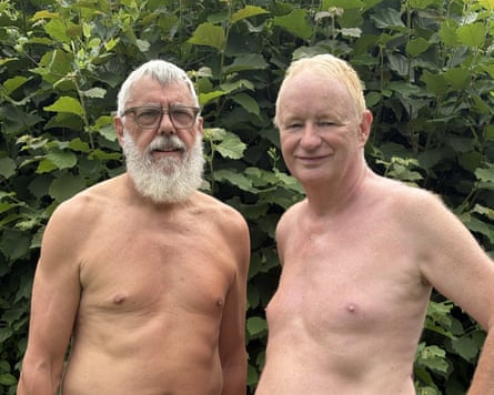 Two naked men standing side by side in front of shrubbery Two naked men standing side by side in front of shrubbery