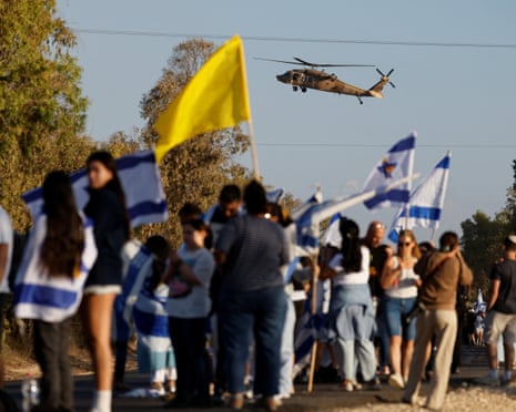 A helicopter flies as people gather in Reim, southern Israel, on Monday