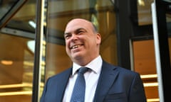 man wearing suit and blue tie smiles in front of glass door
