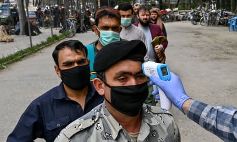 A health worker checks the body temperature of men waiting for Friday prayers outside a mosque in Kabul. 