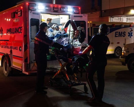 Paramedics load an injured person into an ambulance at night