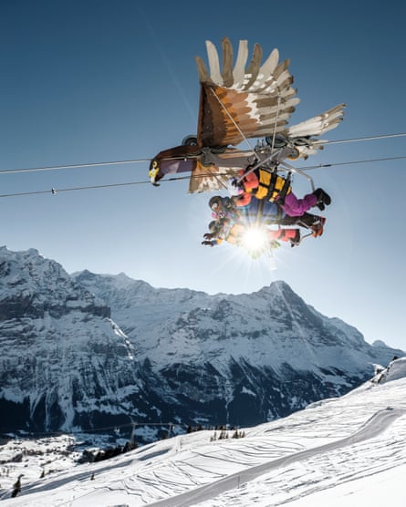 People dressed in ski-wear on a zipline suspended from a large model bird.