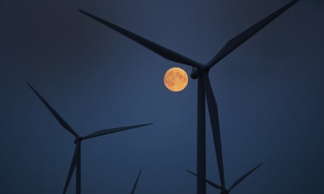 The moon rises behind the wind turbines in Scotland.