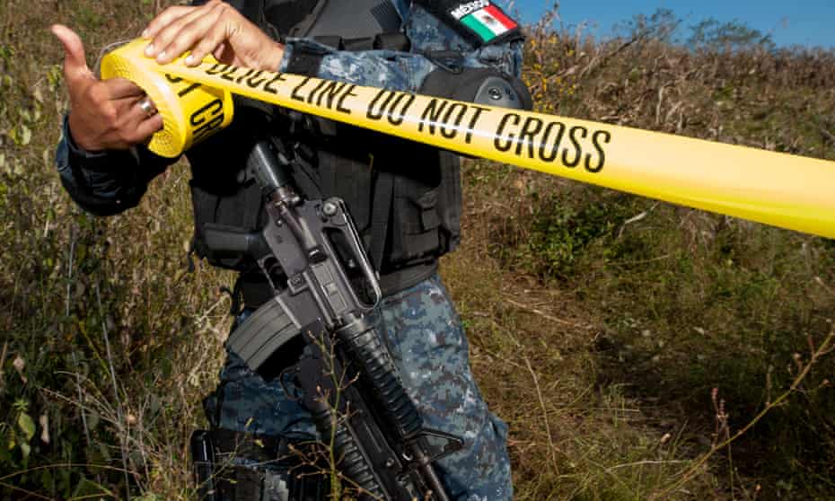 A mexican policeman unrolls crime scene tape