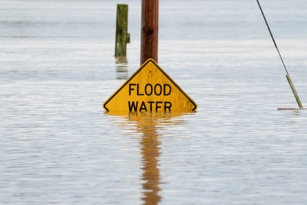 a yellow sign marked ‘flood water’ is partially covered by flood water