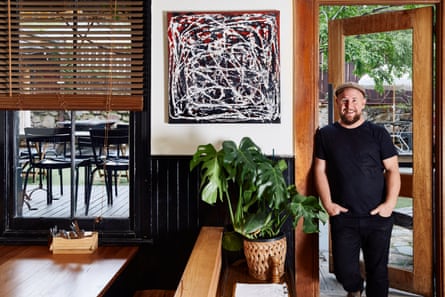 Publican Pat Furze posing next to an abstract artwork by Nicky Winmar