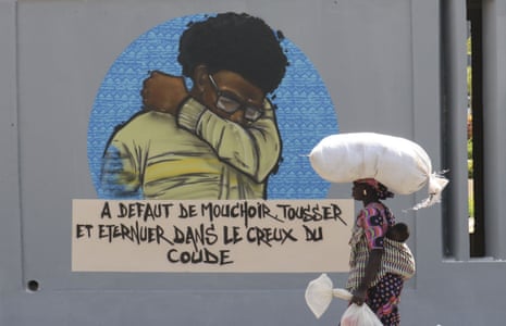 People walk past graffiti on the wall depicting hygienic steps in Dakar, Senegal on 22 March 2020.