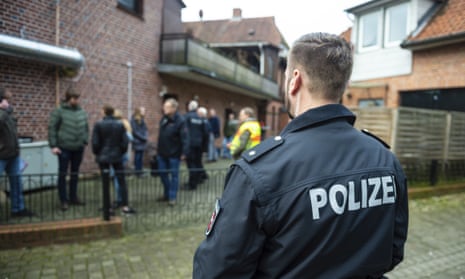 A German police officer stands watch at a house raid.