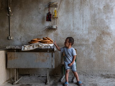 A young boy touches fresh bread from the family tandoor