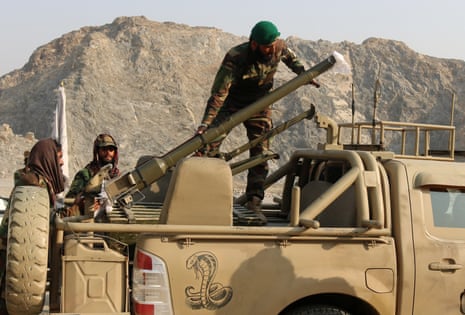 Taliban soldiers load a rocket launcher in a vehicle.