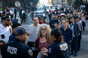 handcuffed people stand in line to be loaded into a bus
