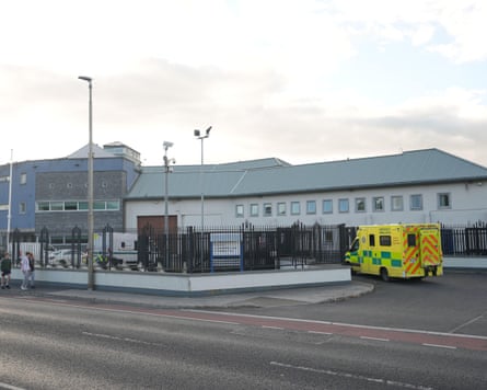 An ambulance outside a a grey prison building