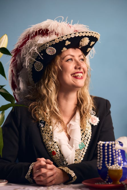 Ashleigh-Rose Harman in her pearly outfit with the impressive hat, sat at a table next to a mother-of-pearl adorned mug