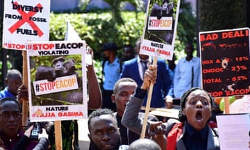 African protesters waving placards with slogans such as "#stop eacop" and "divest from fossil fuels"