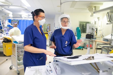Tracy Newey, left, and Anda Ivan discuss the welfare of a patient. Both medics are wearing PPE to prevent the risk of infection to or from the patient.